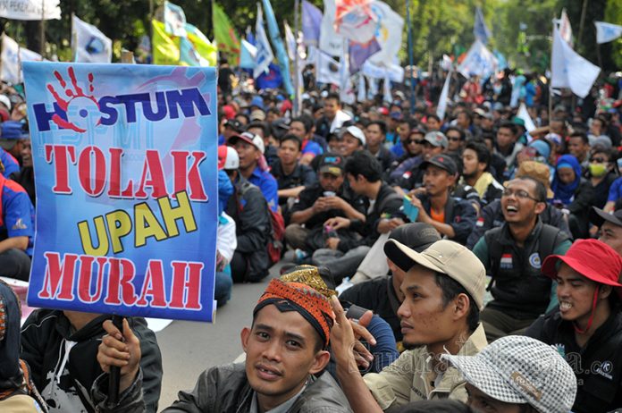 Seorang buruh memegang poster Tolak Upah Murah pada demo menolak kenaikan BBM di depan Istana Negara, Jakarta (10/12). (Foto: Fajrul Islam/SuaraJakarta)