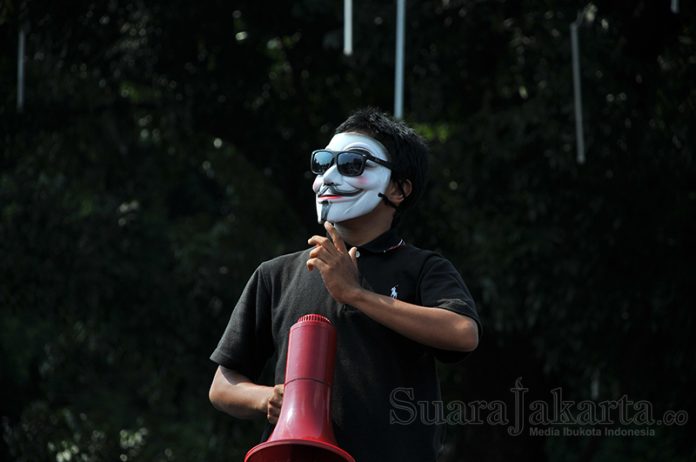 Salah seorang orator aksi mengenakan topeng vendetta sebagai simbol perlawanan. (Foto: Fajrul Islam/SuaraJakarta)